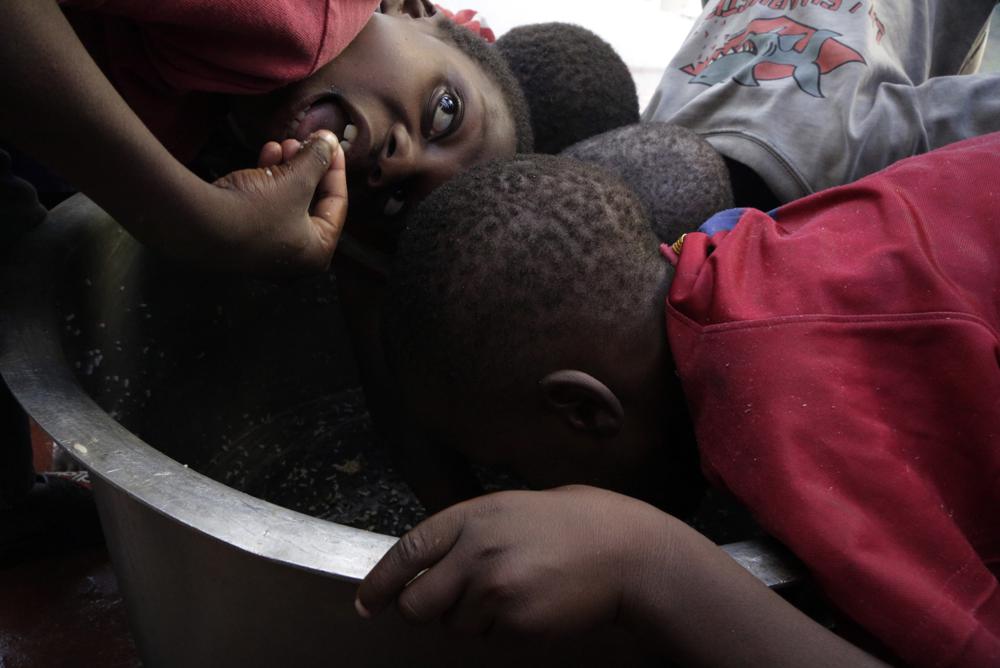 FILE - In this Friday, March 22, 2019 file photo, children scrape through for remaining rice inside a pot at a center for those displaced after Cyclone Idai hit coastal Mozambique, in Beira, Mozambique. The U.N. high commissioner for refugees, Filippo Grandi said Friday June 17, 2021, that conflicts and the impact of climate change in places like Mozambique were among the leading sources of new flows of refugees and internally displaced people in 2020.(AP Photo/Themba Hadebe, File)